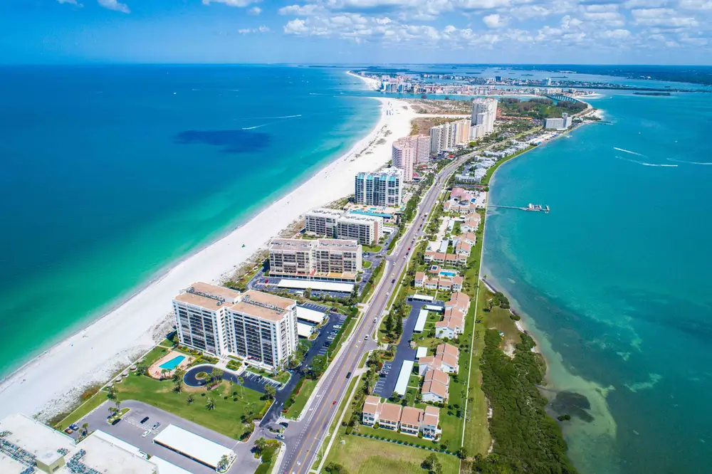 Aerial view of a barrier island with white-sand beaches, hotels and turquoise Gulf water